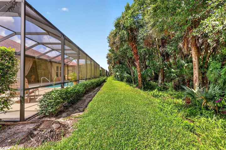 Screen-enclosed pool area with a tiled roofline and surrounding lush foliage