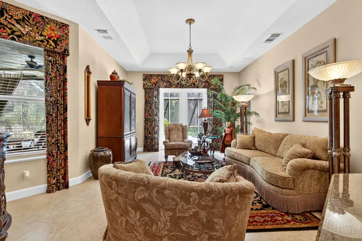 Central chandelier, tray ceiling, tiled flooring, and French doors