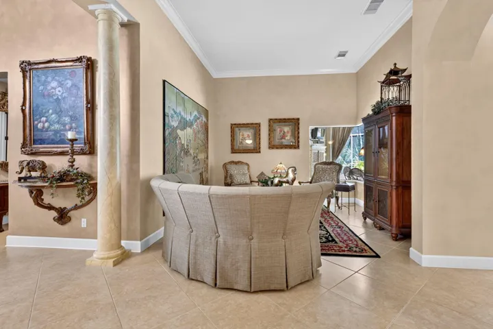 Neutral tone wall finishes, decorative column, crown molding, tile flooring, and vaulted ceilings