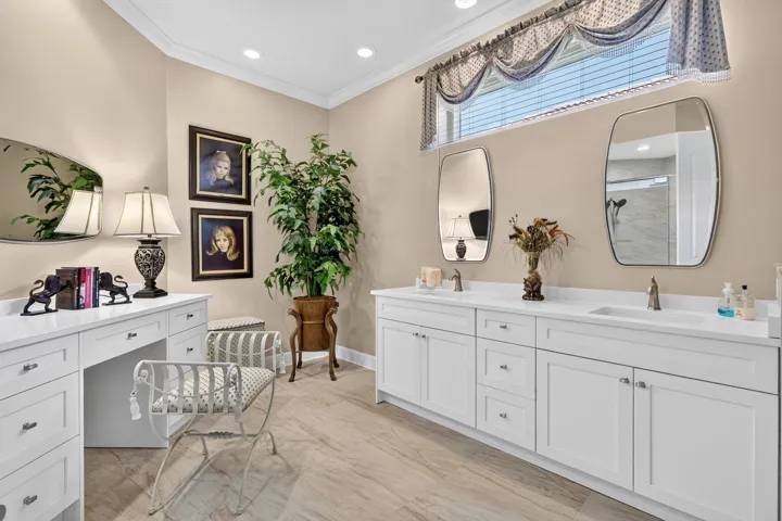 Dual vanity with white cabinetry and integrated sinks, a dedicated vanity desk with storage, elegant crown molding, and recessed lighting