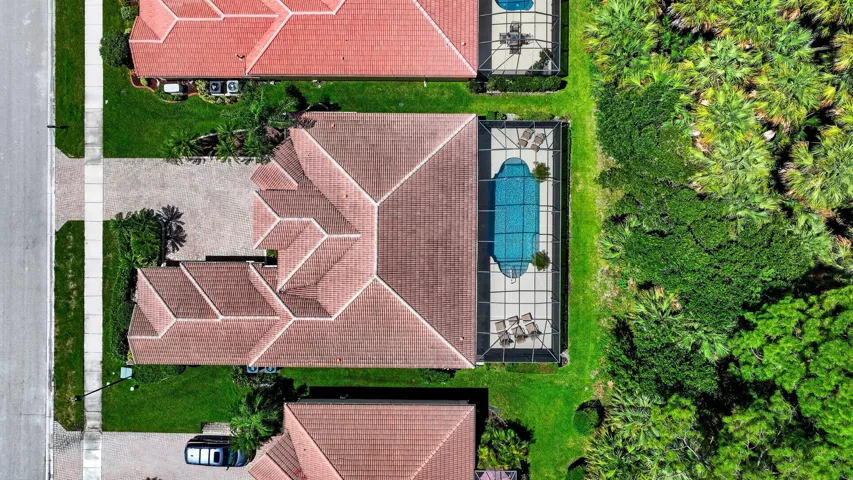 Barrel tile roof, screened swimming pool, paved pool deck, lush green lawn, and mature trees
