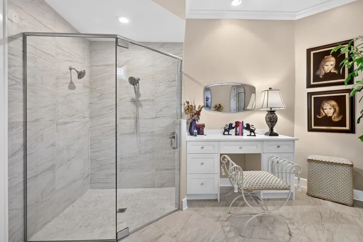 Frameless glass shower enclosure with dual showerheads, tiled walls, and a tiled shower pan