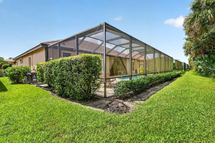 Screened-in pool enclosure featuring a tiled roof and ample patio space