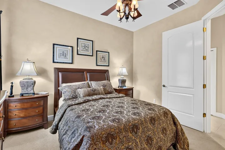 Carpeted bedroom featuring a ceiling fan with integrated lighting, and a white paneled door