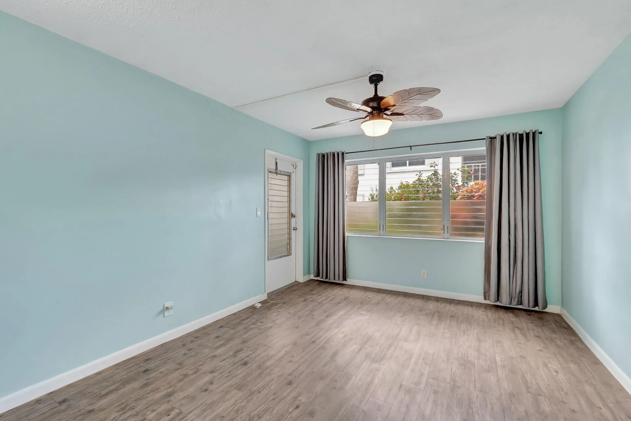 Wood-finish flooring, full-height windows, and a decorative ceiling fan with integrated lighting