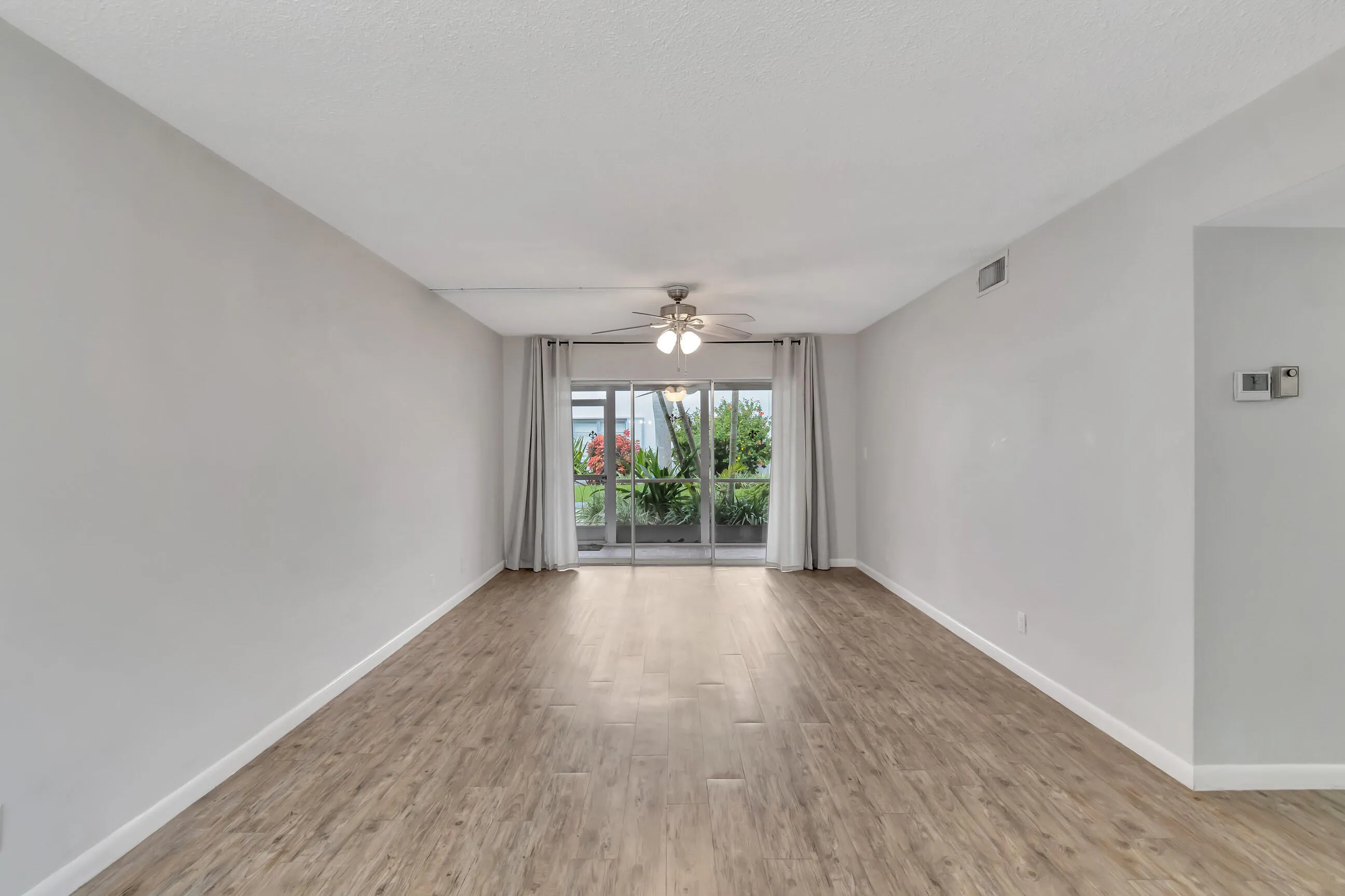 Expansive room featuring wood-finish flooring, light gray walls, and a ceiling fan