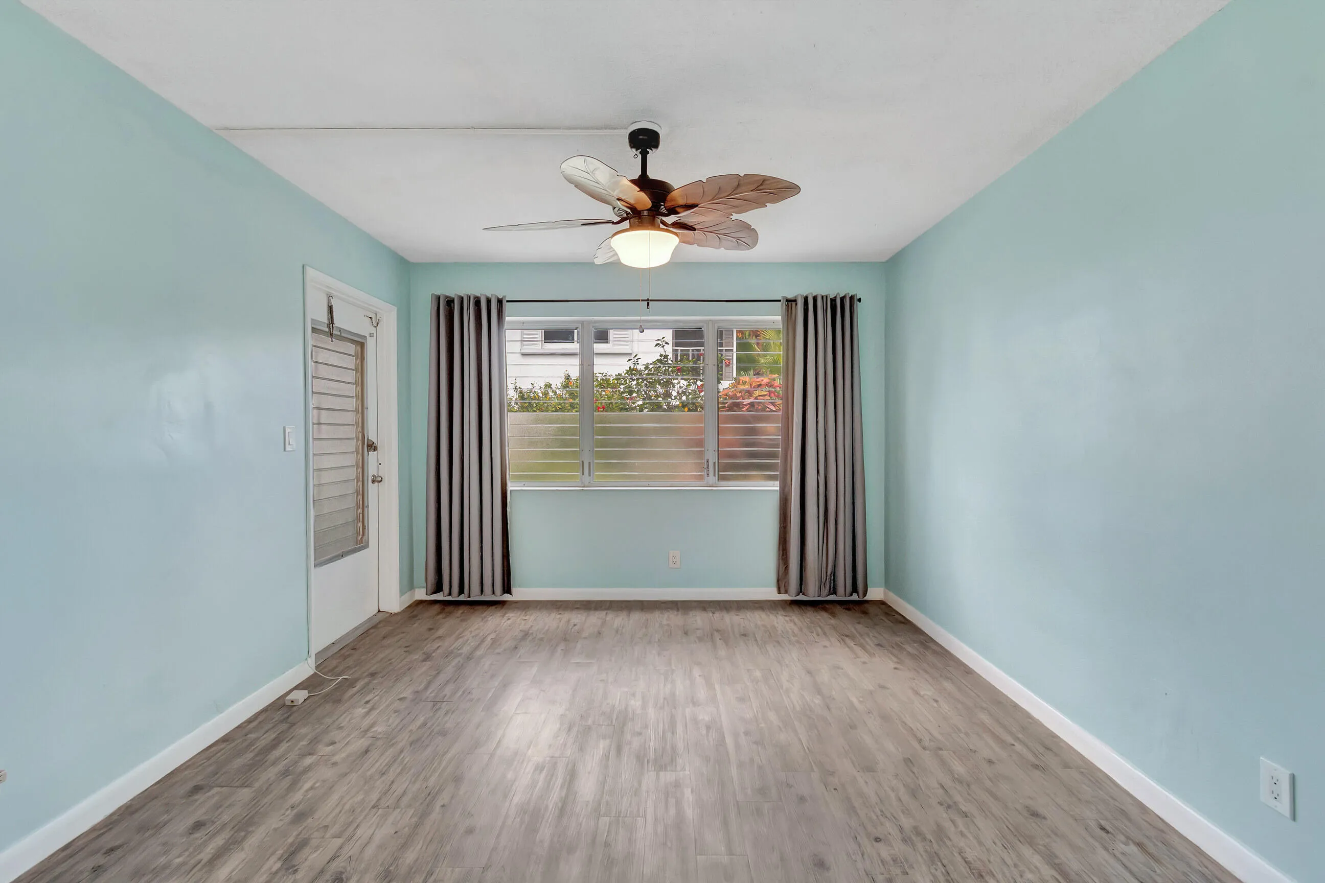 Wood-finish flooring, light blue walls, and a ceiling fan with integrated lighting