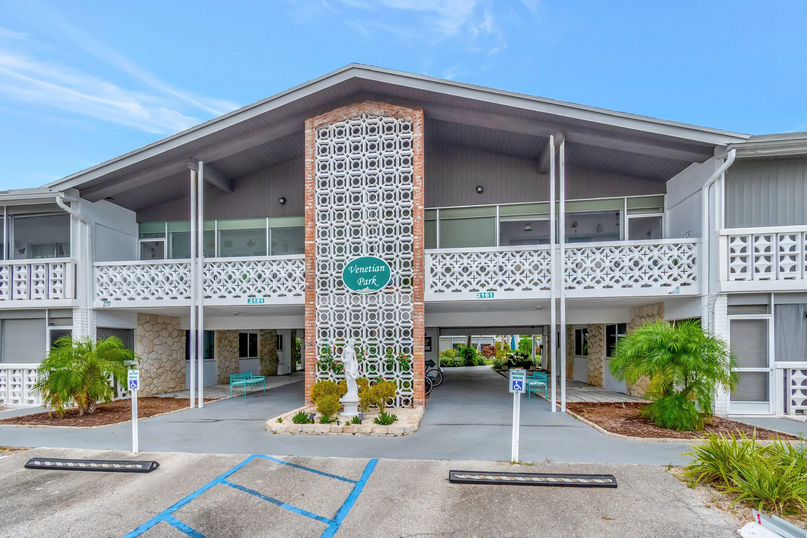 Two-story building featuring a prominent breezeway, decorative architectural block screens, textured stone accents, and an exterior of painted siding