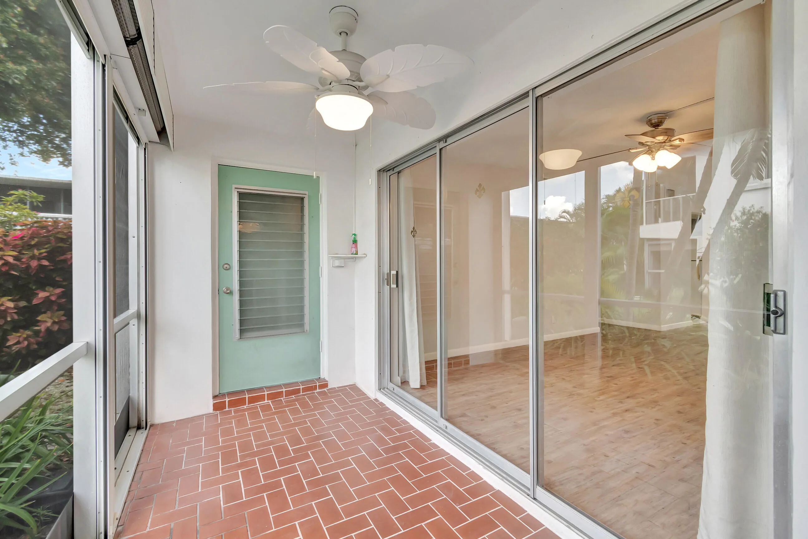 Screened porch featuring a ceiling fan with light, brick-patterned flooring, and sliding glass doors