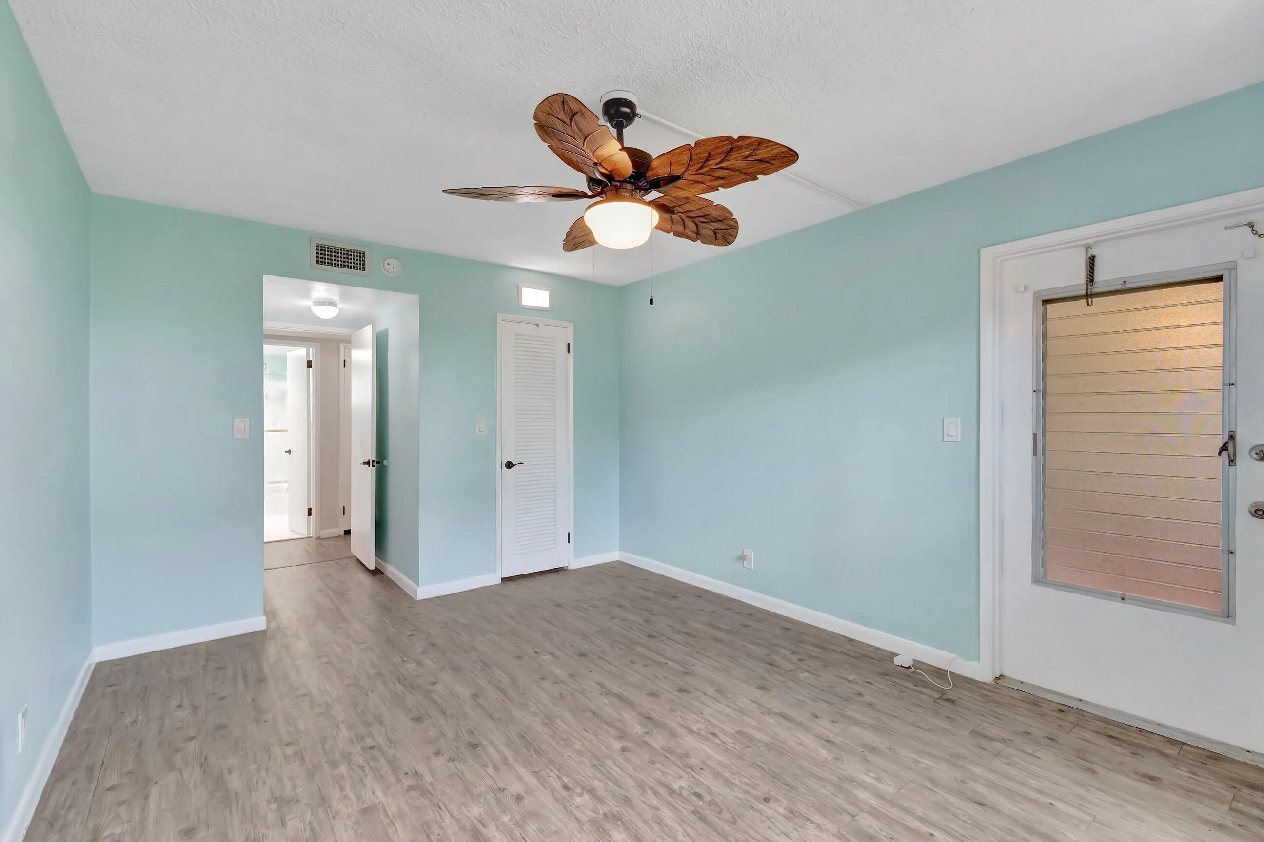 Wood-finish flooring throughout, ceiling fan with tropically-inspired blades, and a textured ceiling