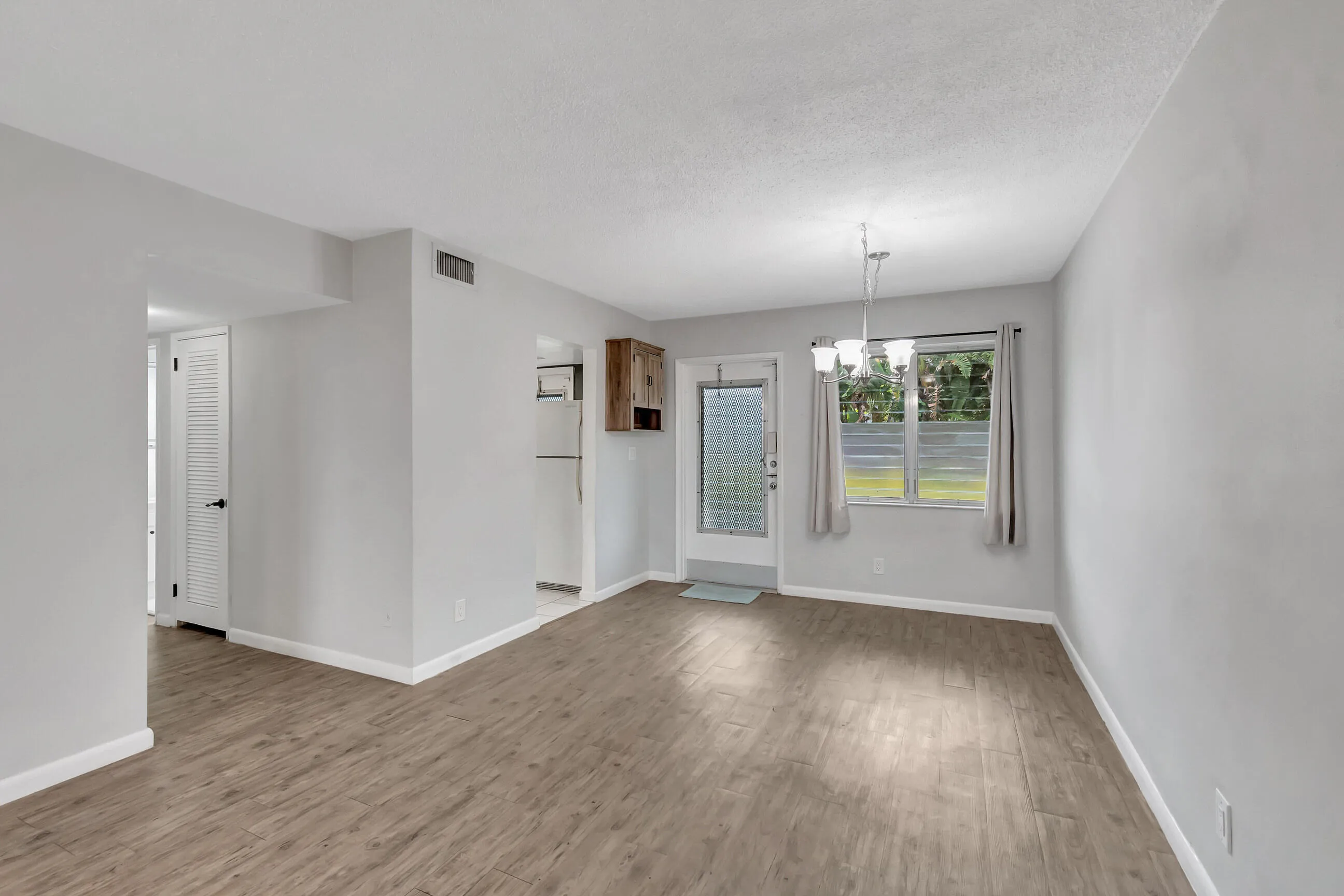 Light-toned walls, wood-finish flooring, and a dining fixture