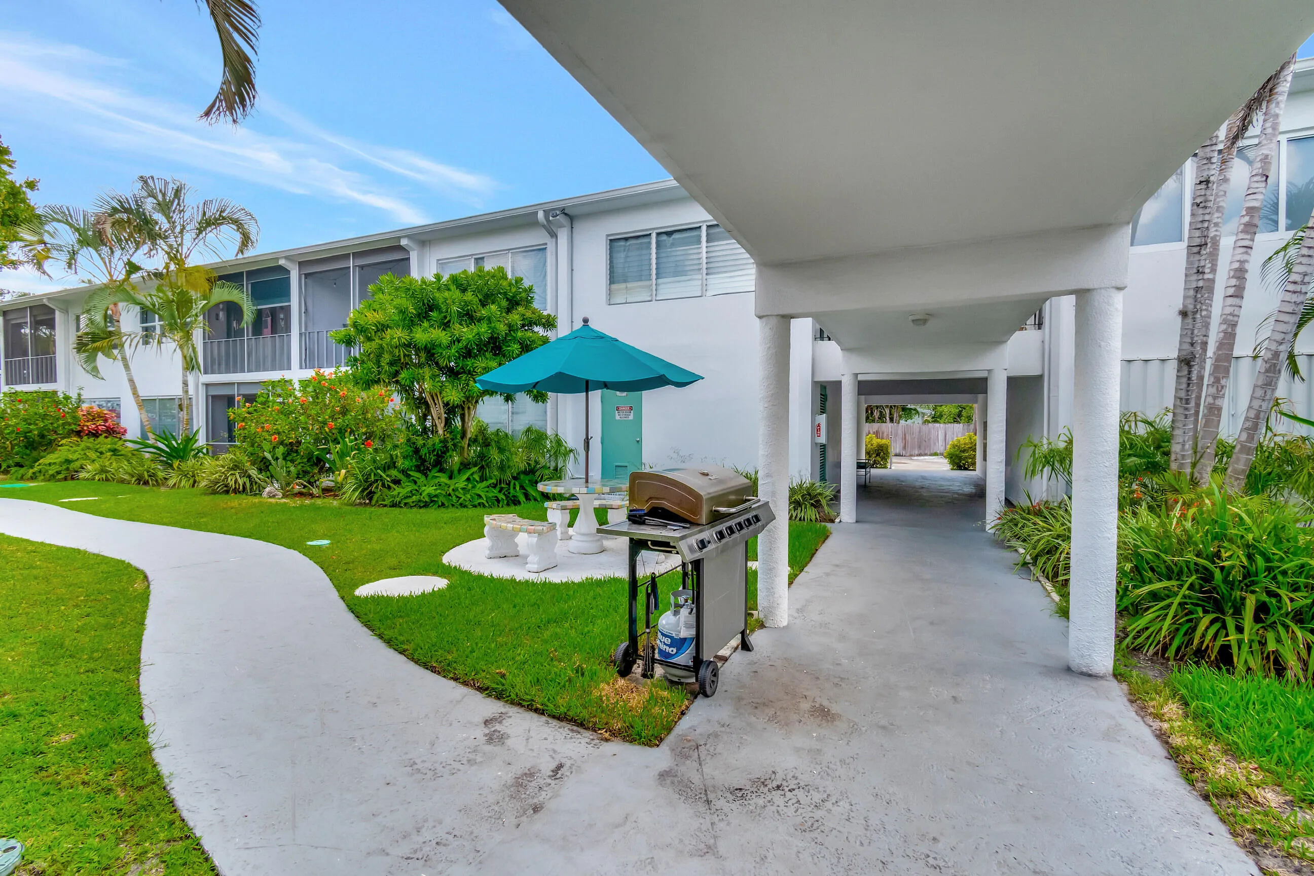 Exterior features include a white stucco facade, screened balconies, and a concrete walkway