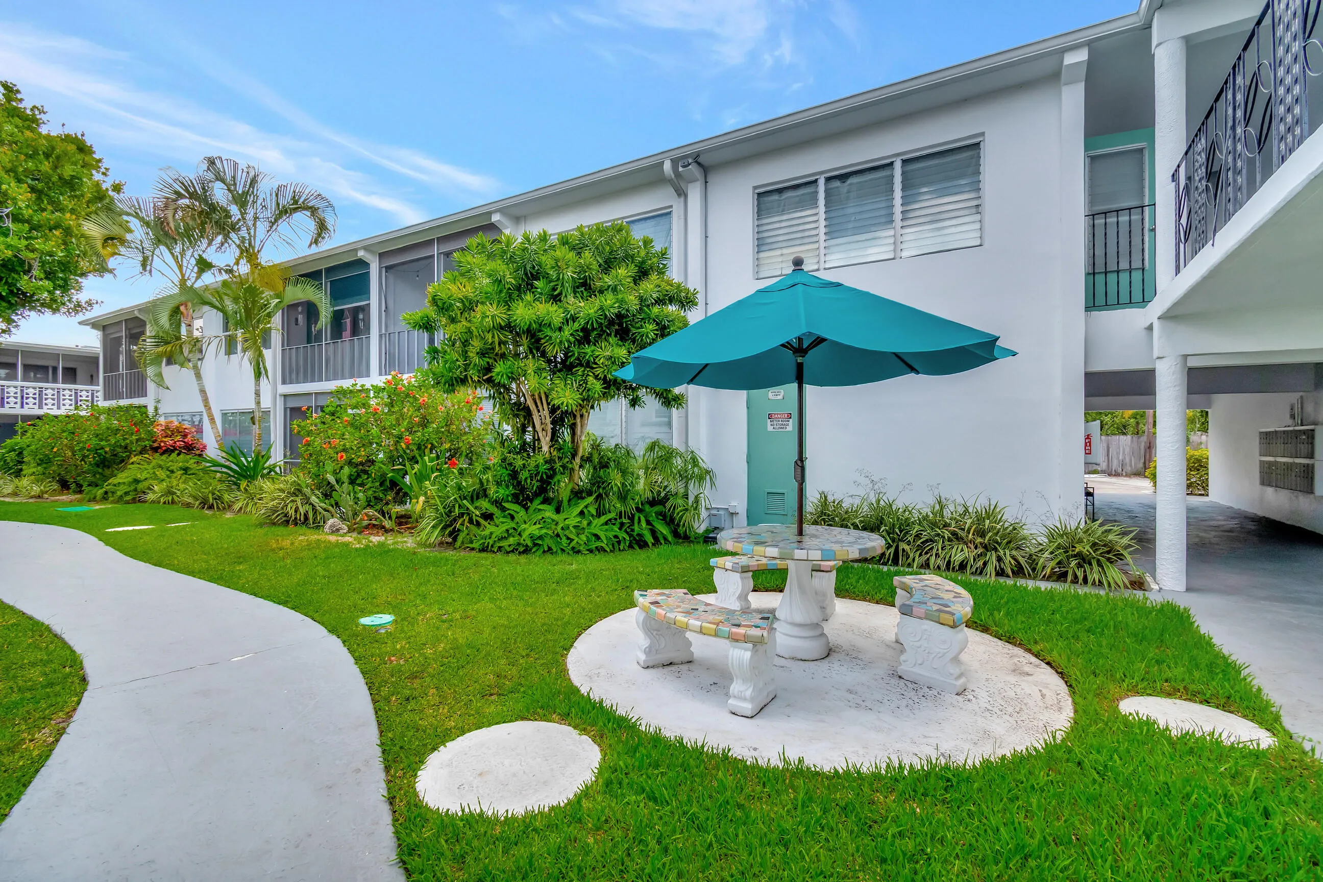 Manicured landscaping, concrete pathways, and a built-in outdoor seating area