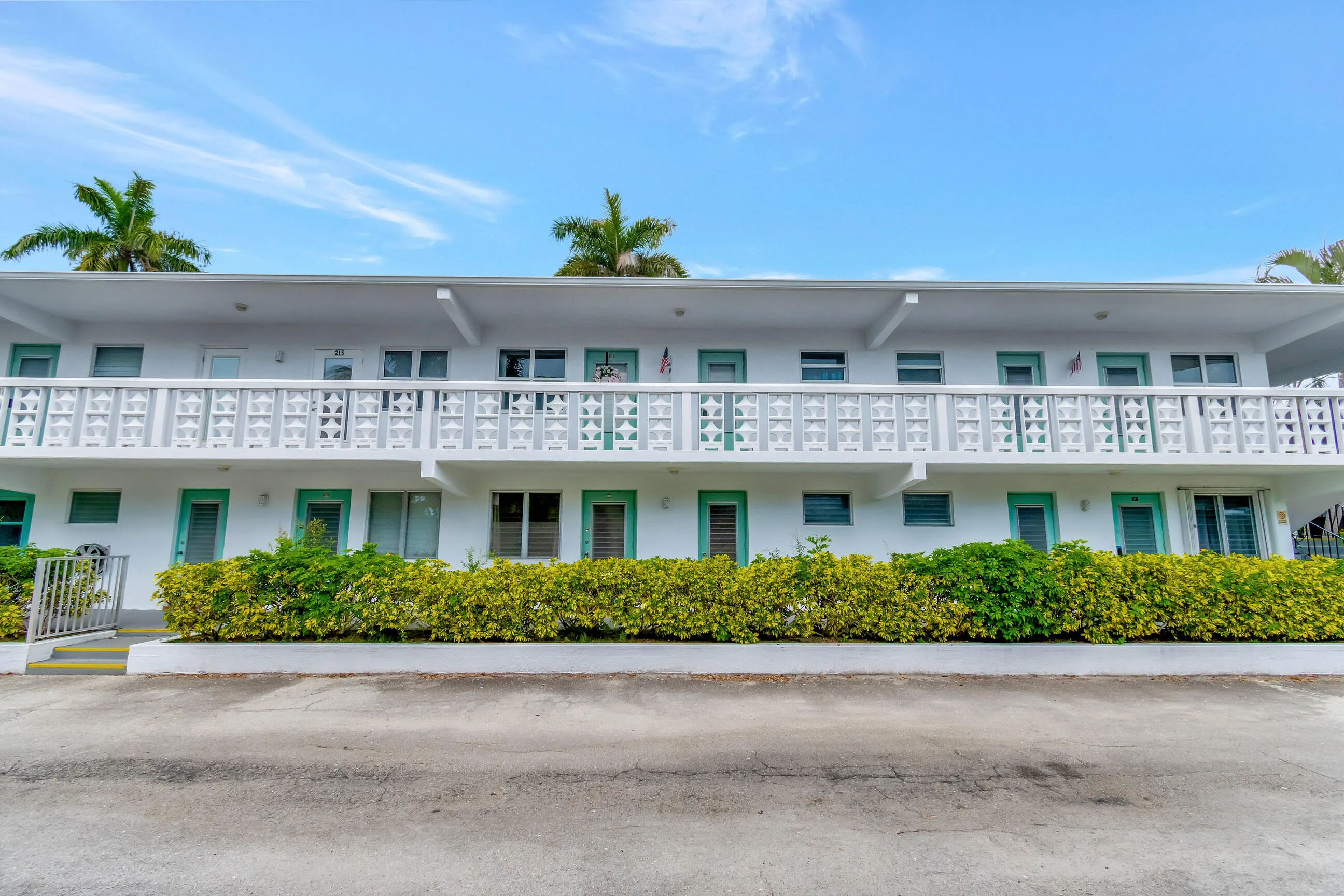 Two-story multi-unit building featuring white stucco exterior and decorative balcony railings