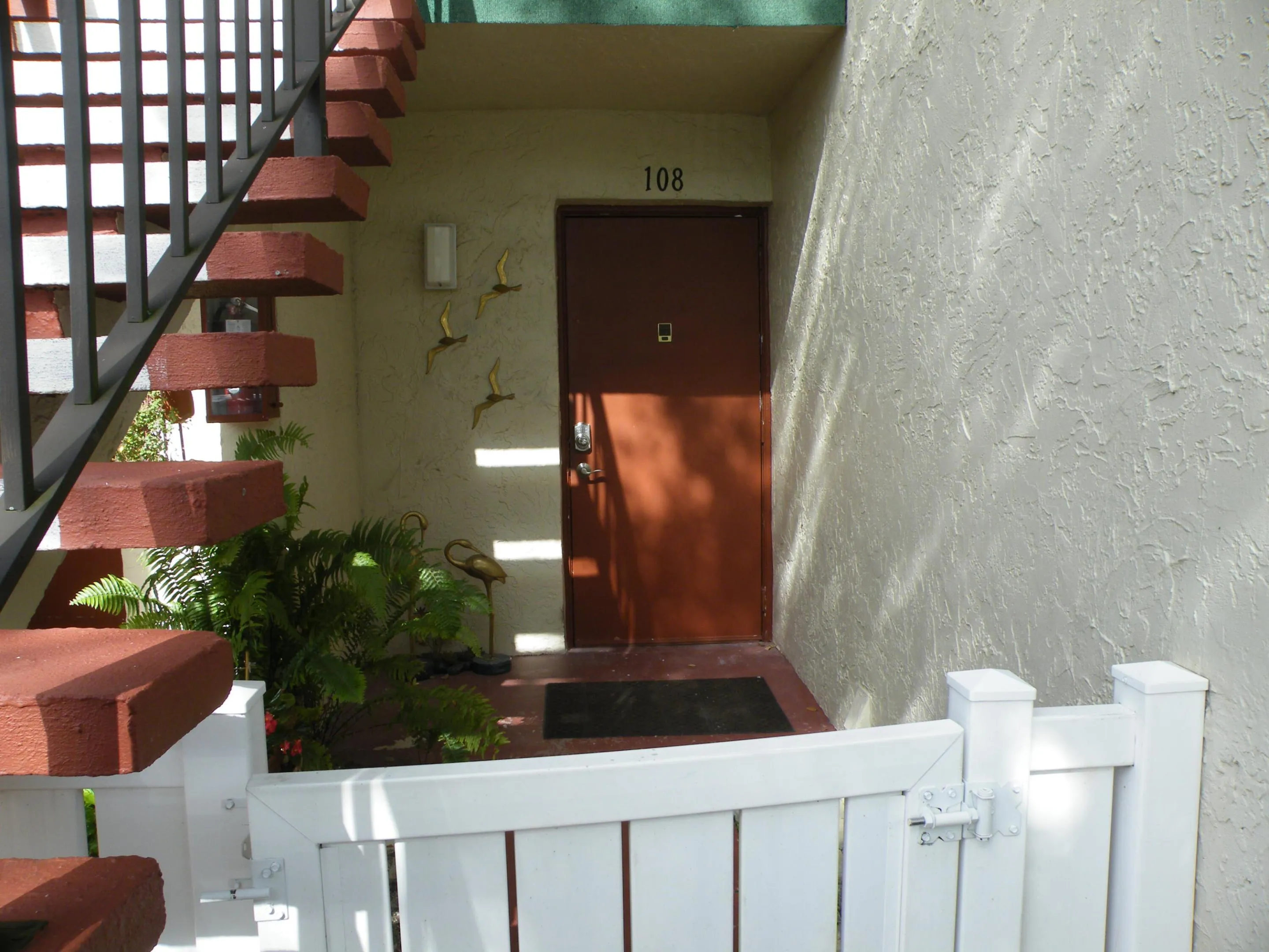Private entrance featuring a white picket fence and a covered entry