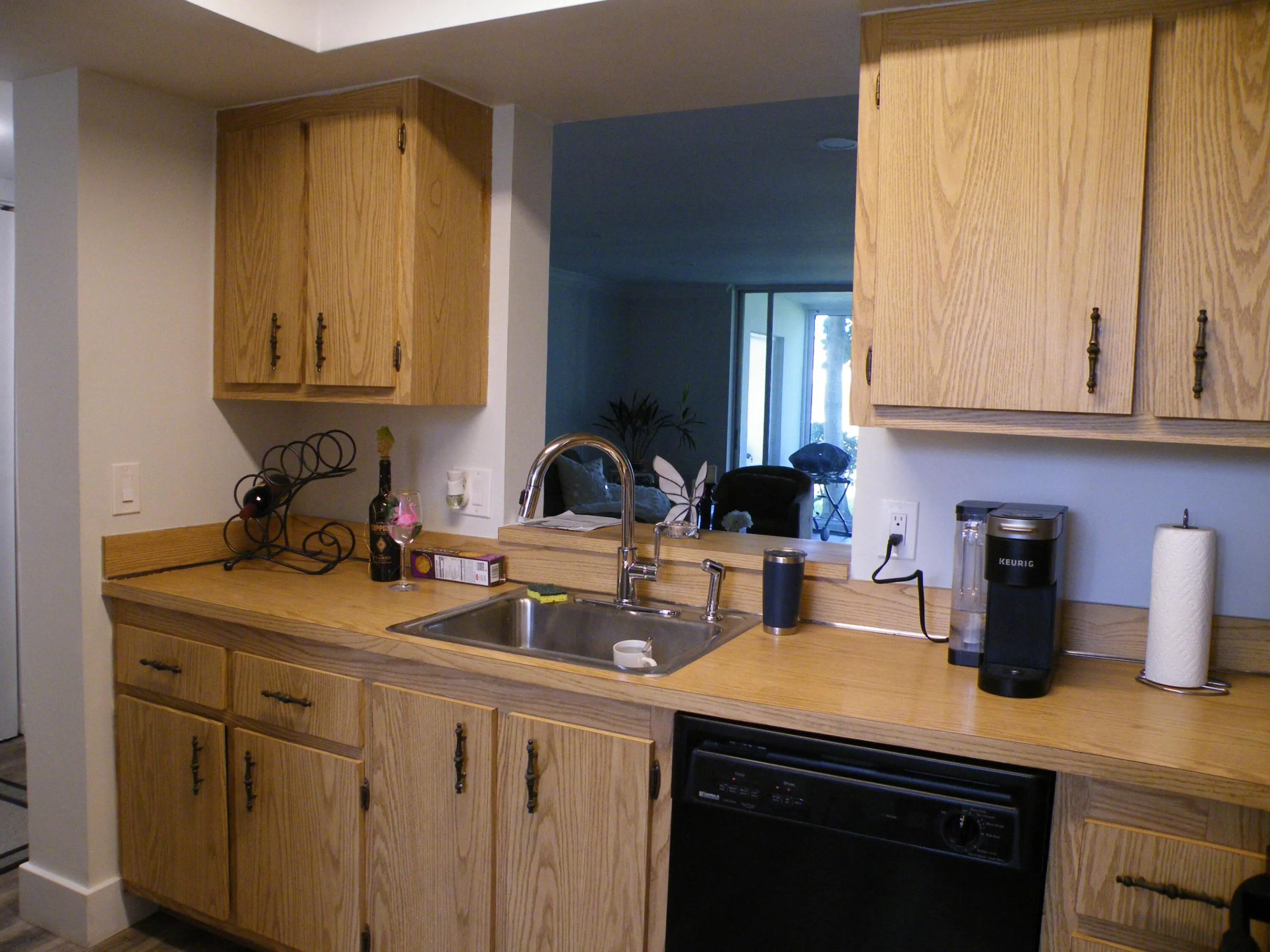 Kitchen featuring wood-finish cabinetry, a stainless steel sink with a high-arc faucet, and black dishwasher