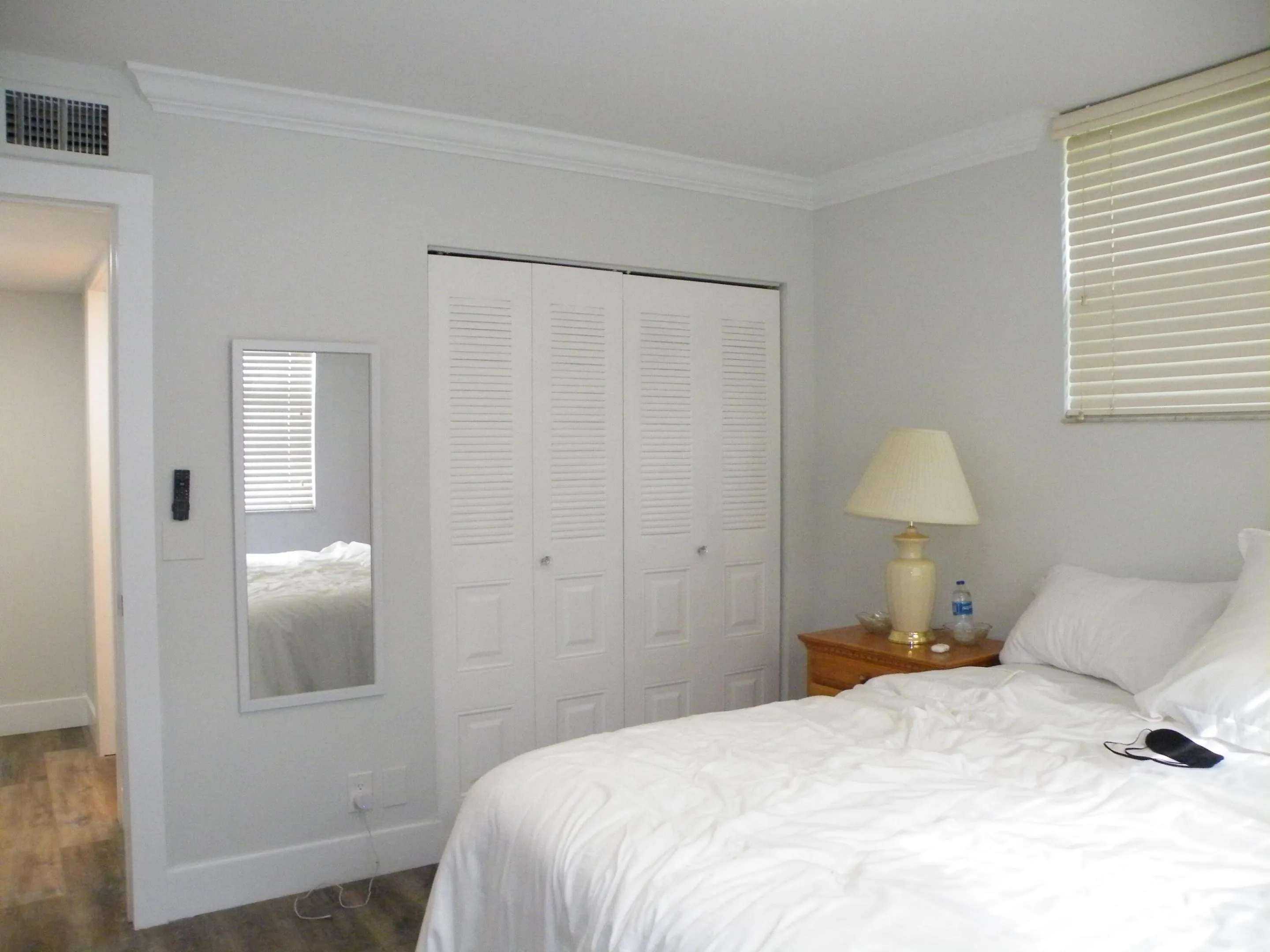 Crown molding detail, louvered bi-fold closet doors, horizontal window blinds, wood-finish flooring