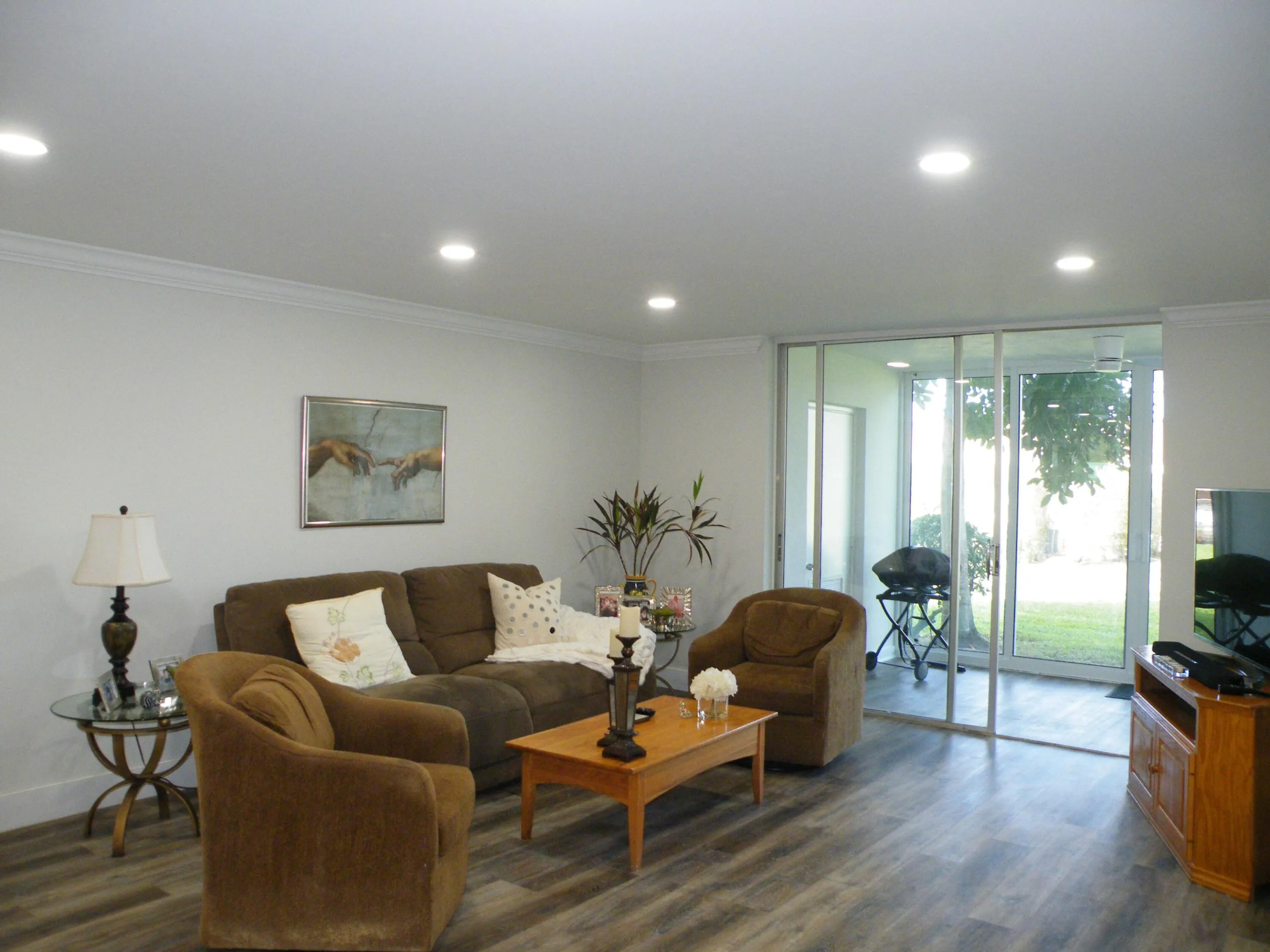 Recessed ceiling lighting, crown molding, wood-finish flooring, and sliding glass doors