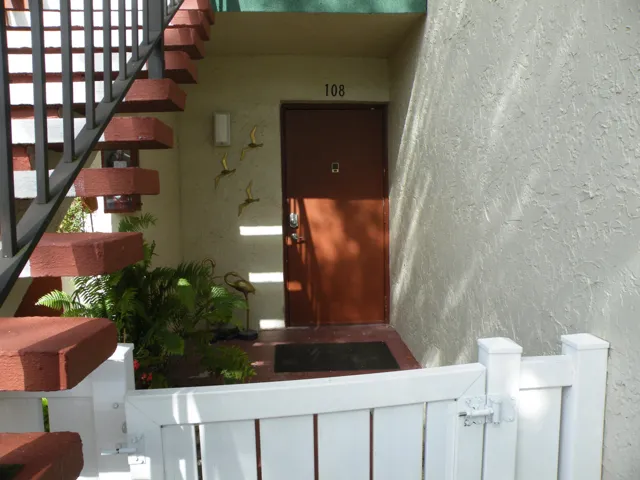 Private entrance featuring a white picket fence and a covered entry
