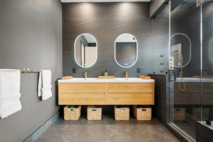 Sculpted wave tile, brushed brass fixtures, backlit mirrors — impeccable
