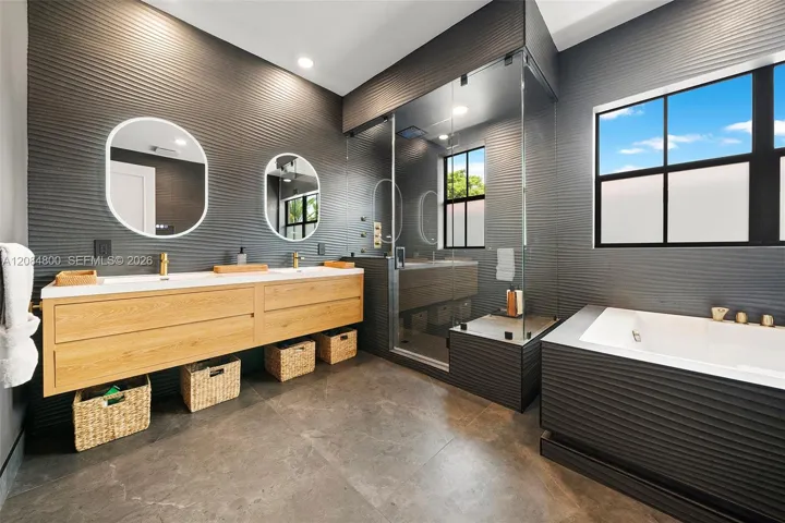 Dual-sink floating vanity with backlit mirrors and brass fixtures in the spa-like primary bath