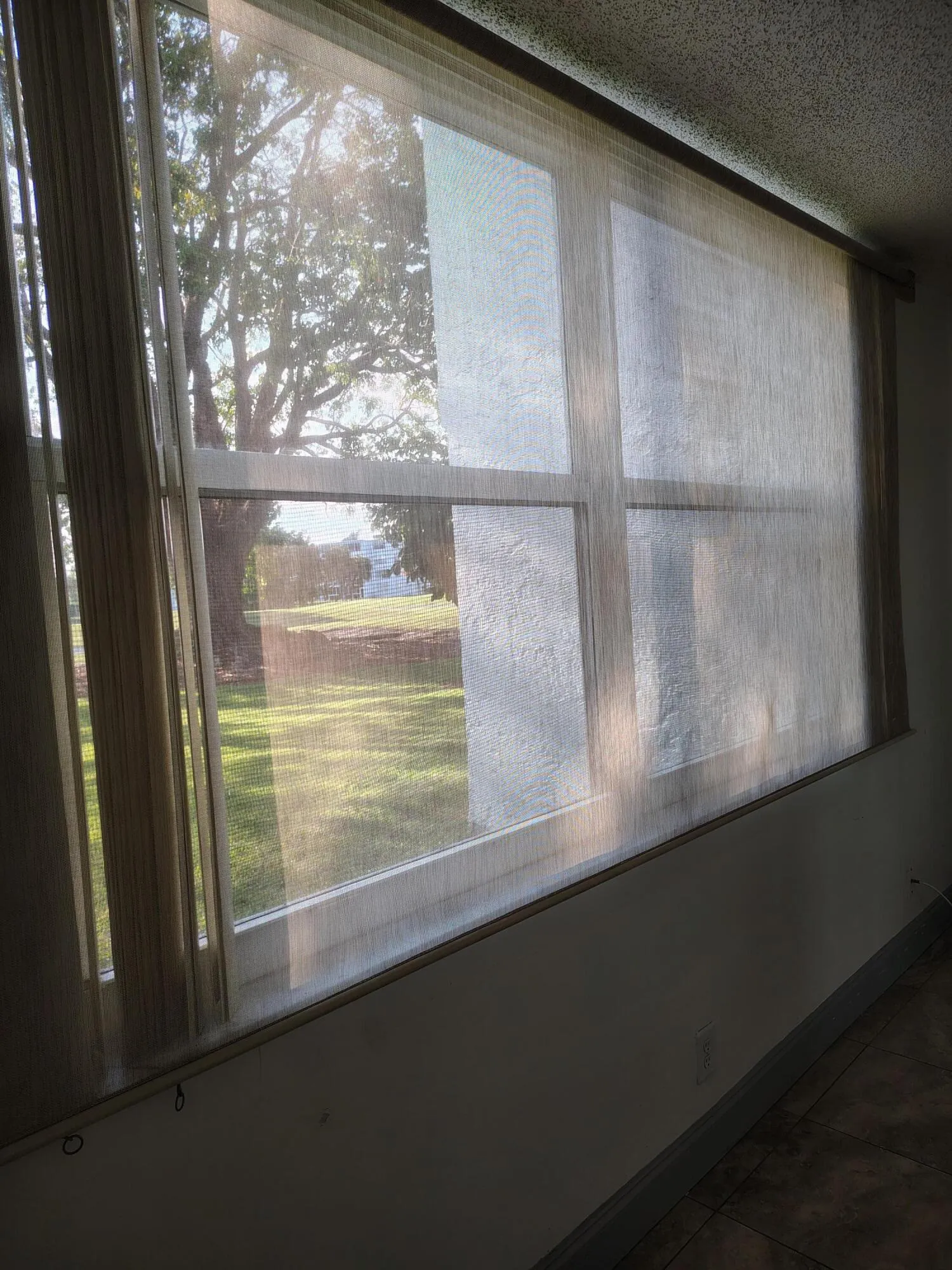 Huge Bedroom Window With Verticals And Mesh Window Treatment