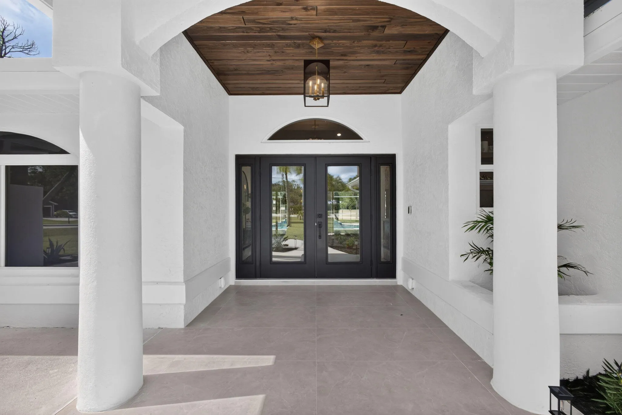 Double door entrance with impact glass, custom lighting, and wood ceiling detail