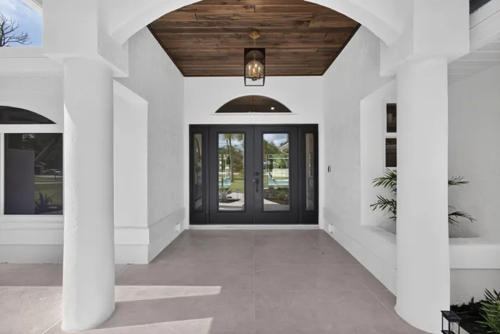 Double door entrance with impact glass, custom lighting, and wood ceiling detail