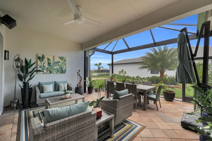 Expansive screened lanai featuring an outdoor dining area, ceiling fan, and tile flooring