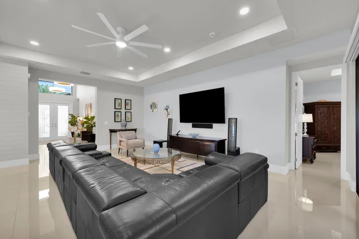 Recessed lighting, ceiling fan, tray ceiling, tile flooring, and white double entry doors