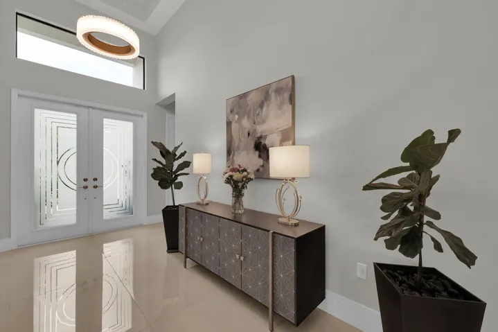 Double entry doors with patterned frosted glass, transom window, and a vaulted ceiling with a circular chandelier