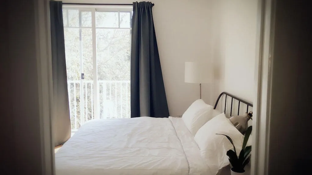 Sliding glass door with white frame, white balcony railing, and dark curtains