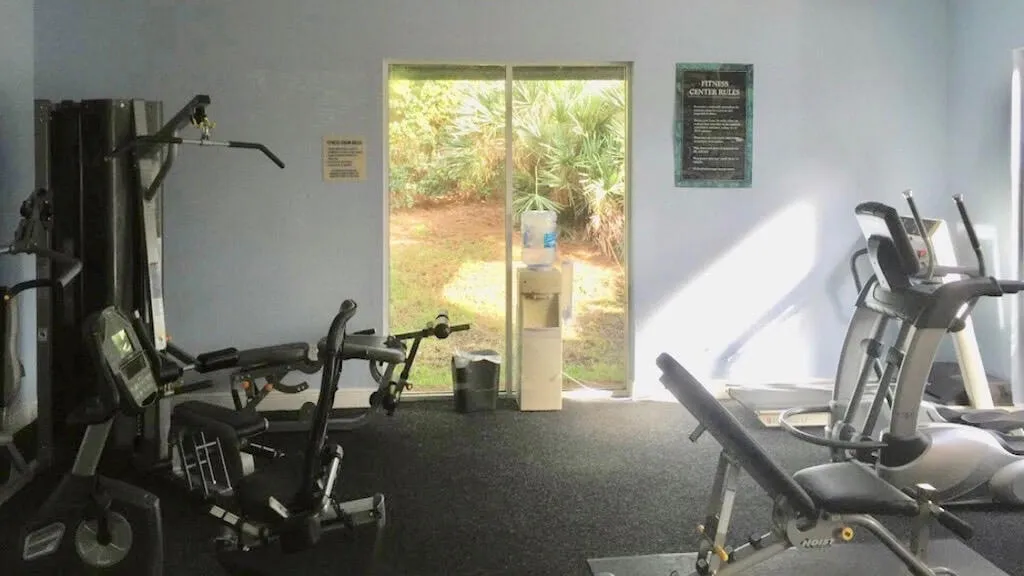 Dedicated fitness center featuring exercise equipment, rubber flooring, and large windows