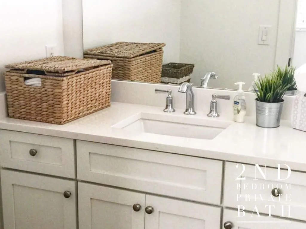 White vanity with shaker-style cabinetry, an integrated rectangular sink, a wide-set chrome faucet, and a large wall-mounted mirror