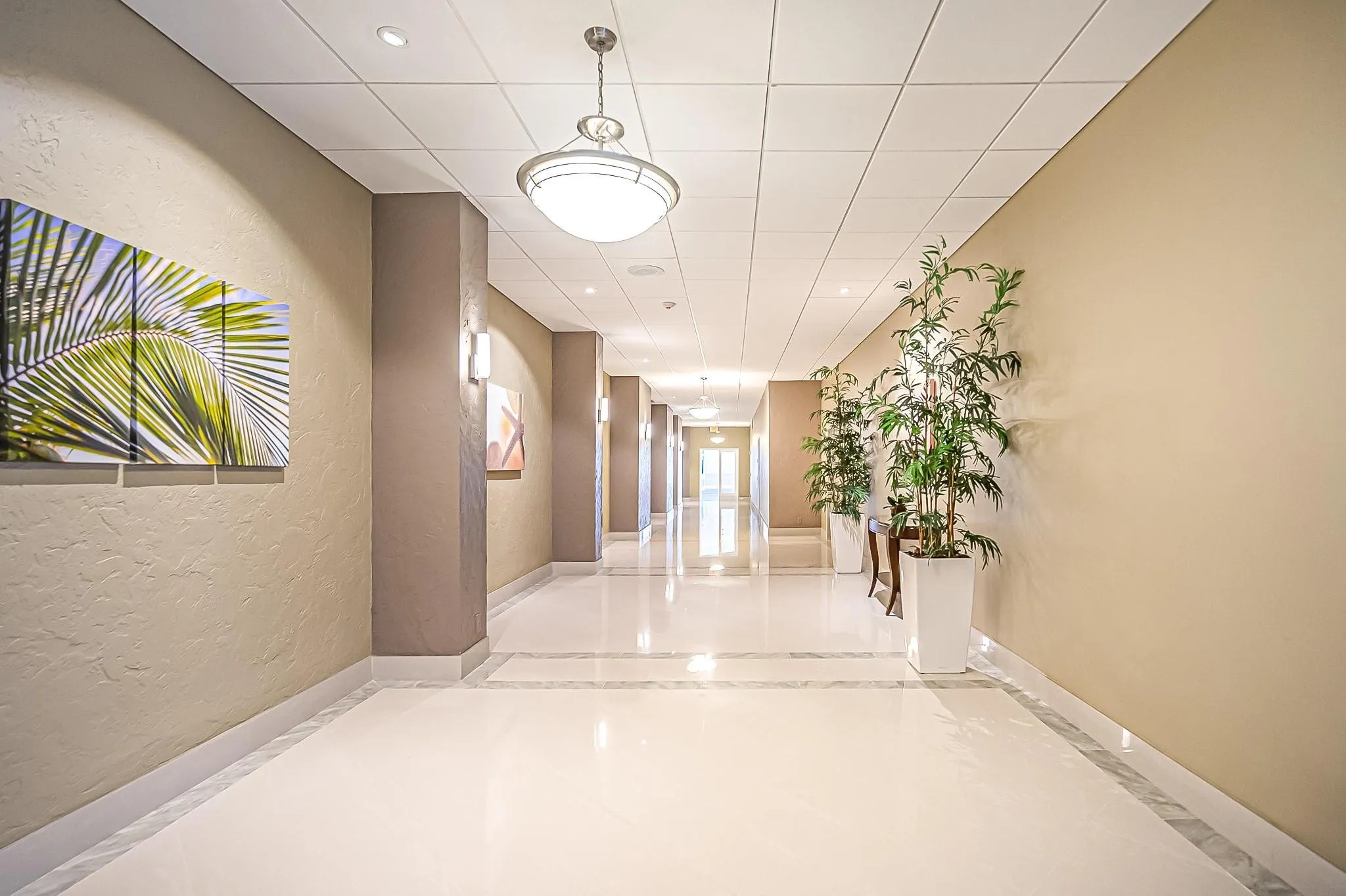 Hallway featuring polished tile flooring, recessed lighting, and decorative wall sconces