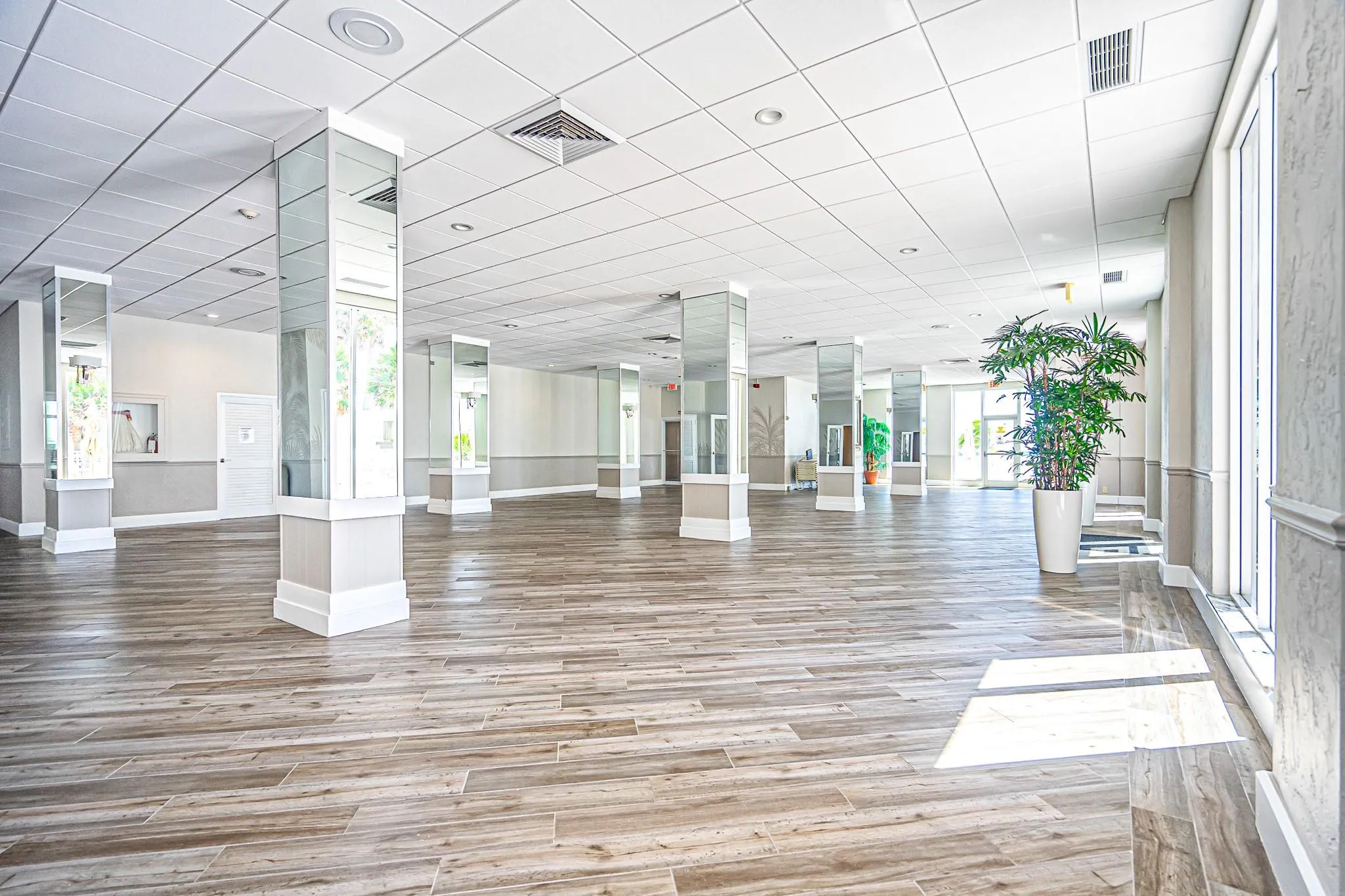 Spacious open layout featuring wood-finish flooring and reflective pillar accents