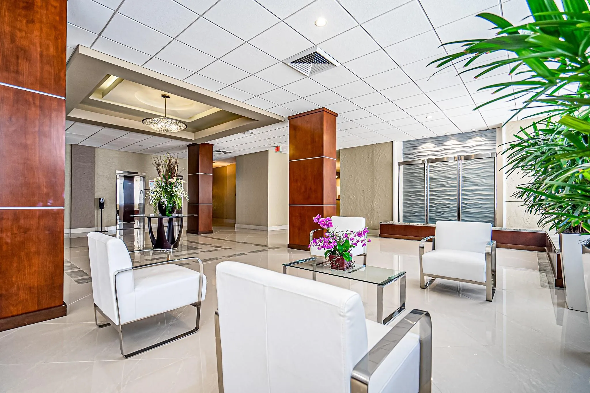 Polished tile flooring, wood-paneled columns, recessed lighting, and a decorative chandelier create a sophisticated ambiance