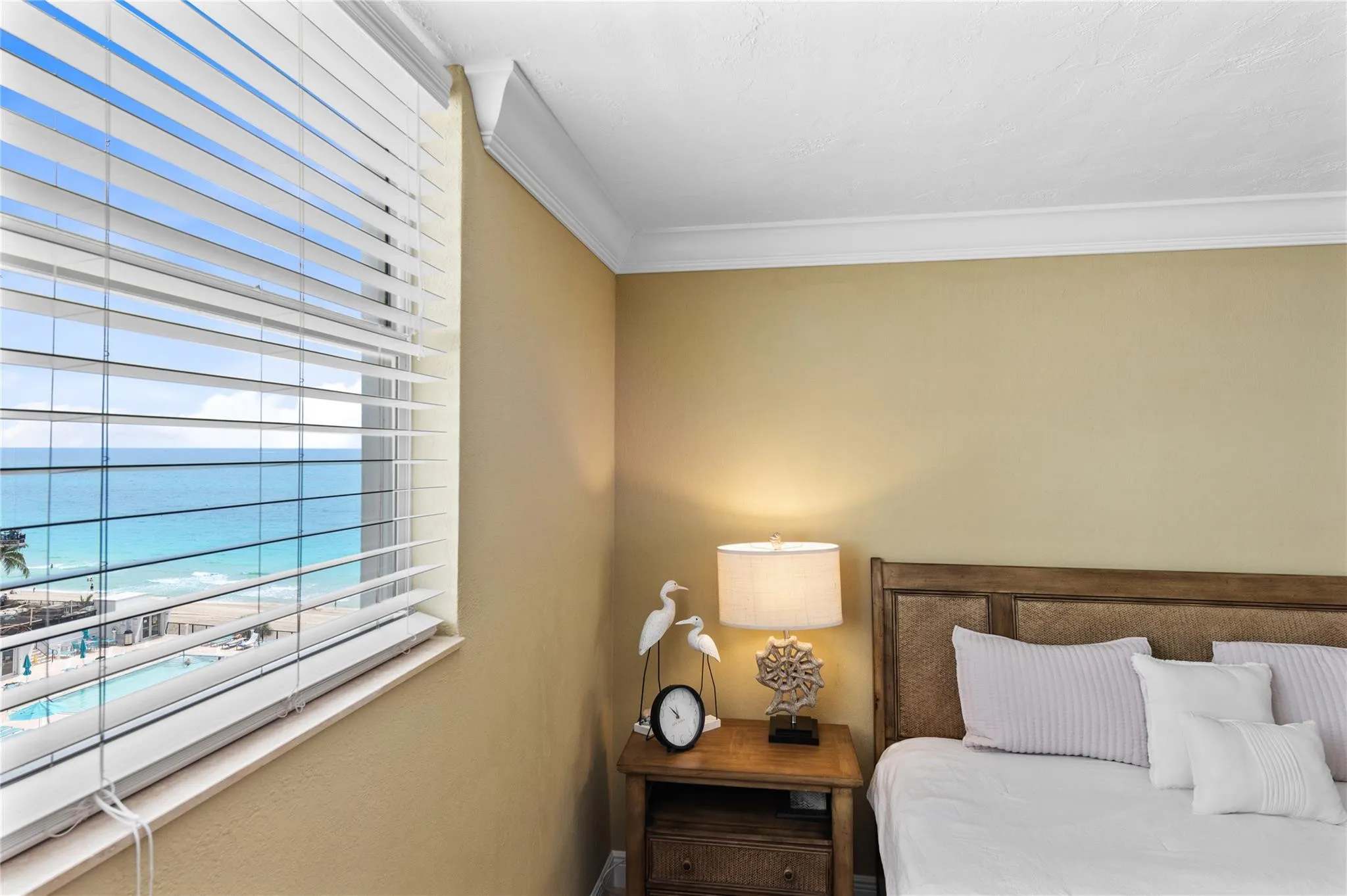 Expansive window with horizontal blinds, offering a prominent ocean backdrop
