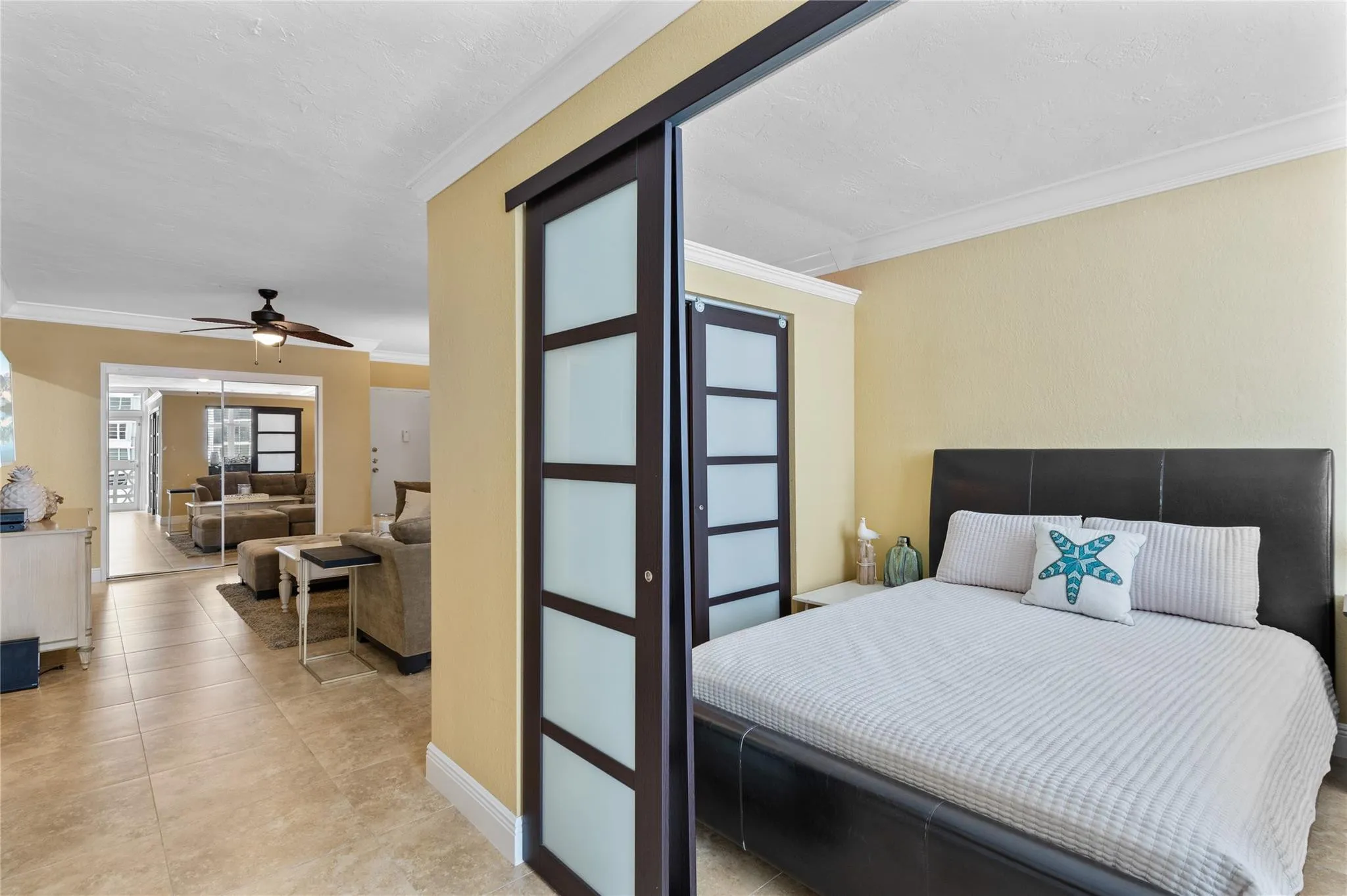 Sliding panel doors with frosted inserts, tile flooring, crown molding, and a ceiling fan with light fixture