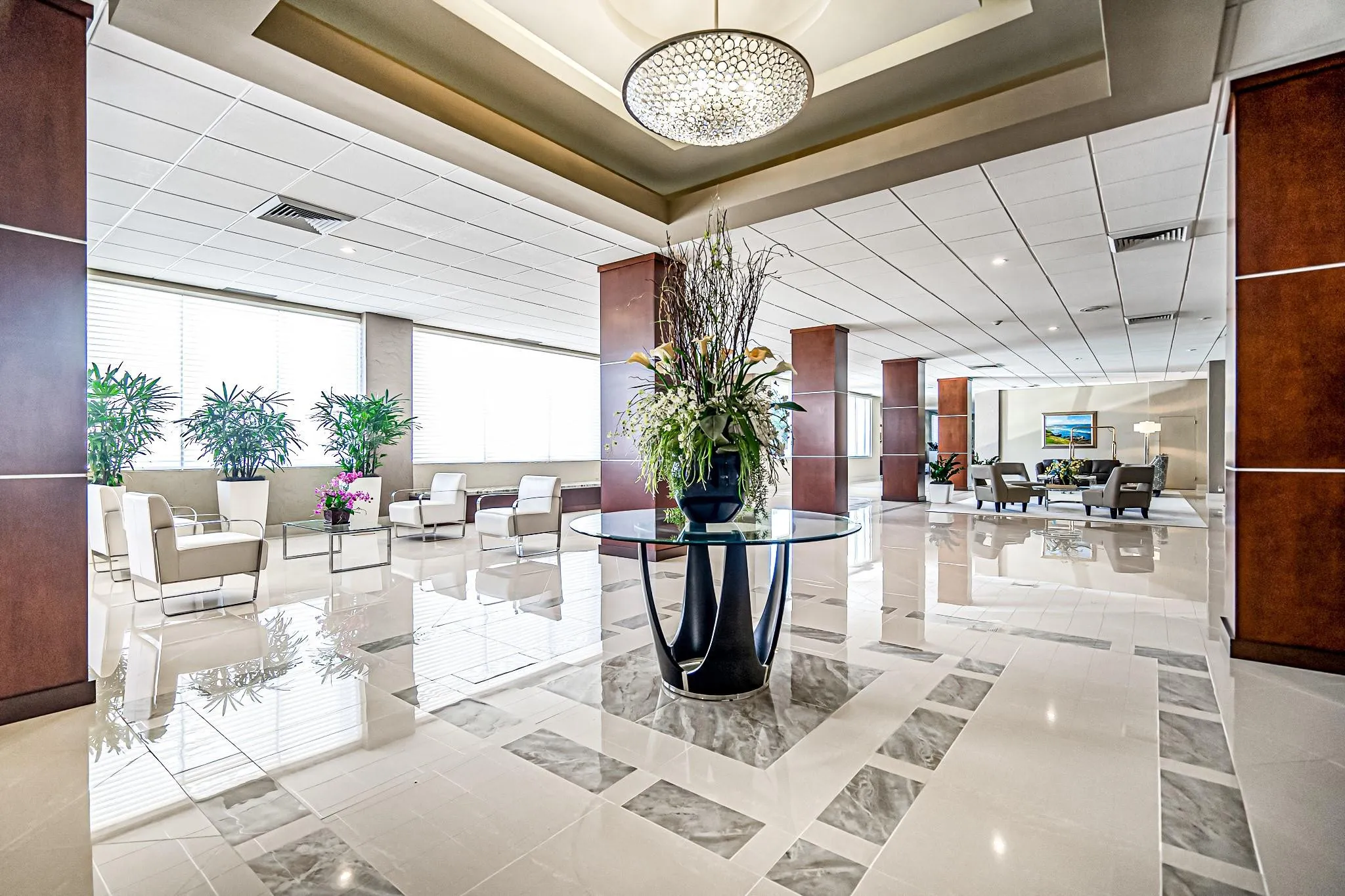 Expansive lobby featuring polished tile flooring with decorative inlay, contemporary chandelier, and large windows