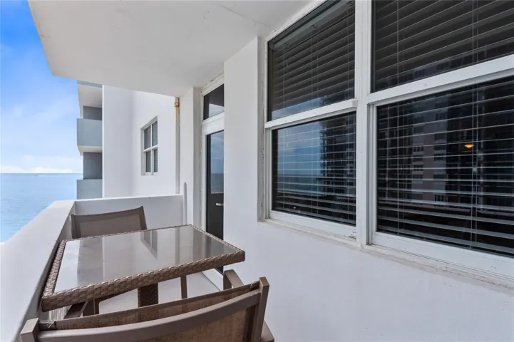 Private outdoor balcony featuring a painted concrete railing and a scenic water backdrop