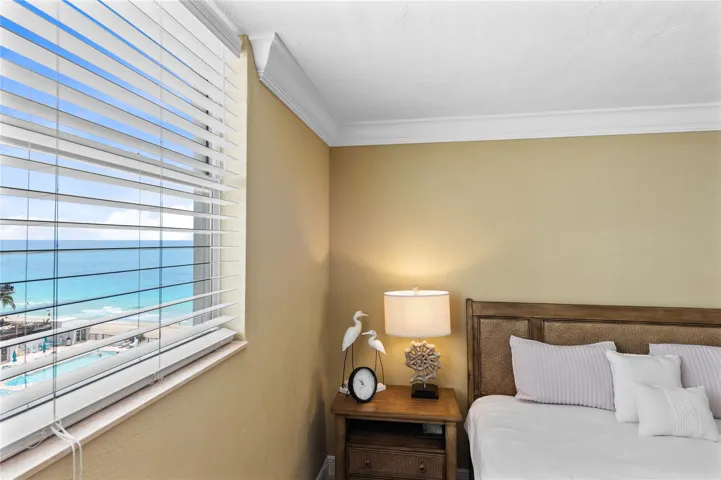 Expansive window with horizontal blinds, offering a prominent ocean backdrop