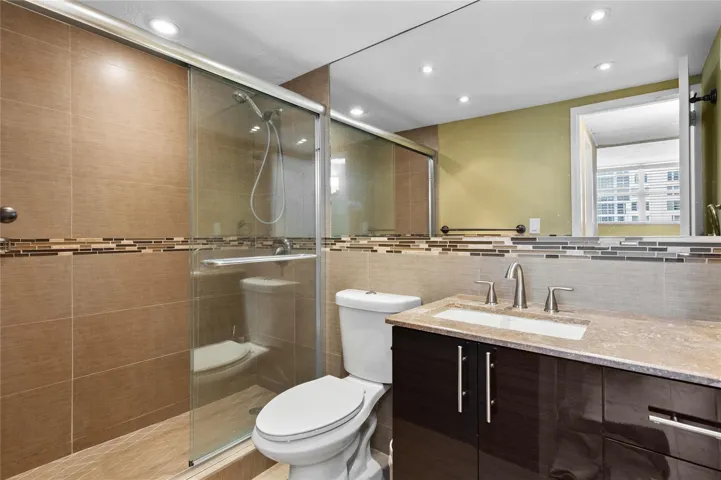 Glass-enclosed shower with a tiled surround, integrated tile accent band, and recessed lighting