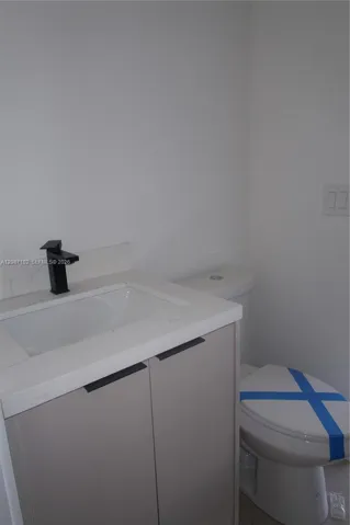Bathroom 2. Modern vanity featuring a light-toned cabinet, white countertop, integrated rectangular sink, and matte black faucet