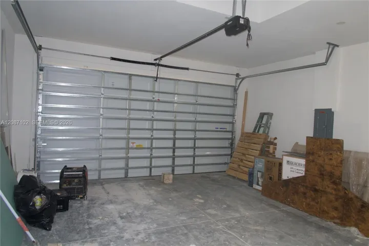 2 car garage, Enclosed garage featuring a white paneled overhead door, concrete flooring, and an automated door opener