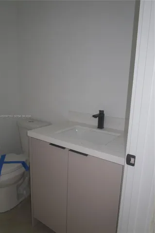 Bathroom 3, Modern vanity featuring a stone-surface countertop, rectangular undermount sink, and matte black faucet, paired with a two-door storage cabinet and an integrated toilet