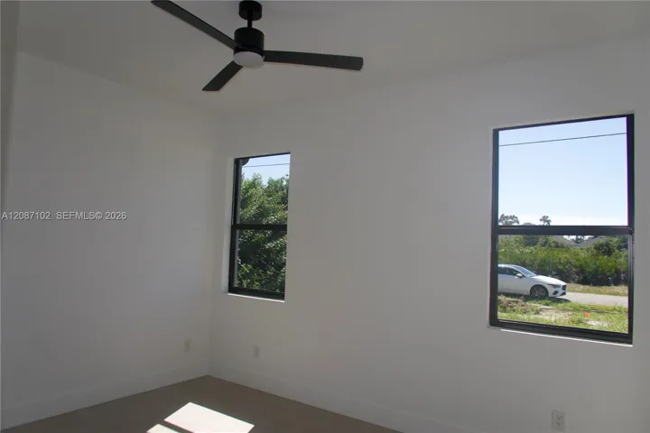 Bedroom 3, Neutral wall tones, carpeted flooring, black-framed windows, and a matte black three-blade ceiling fan