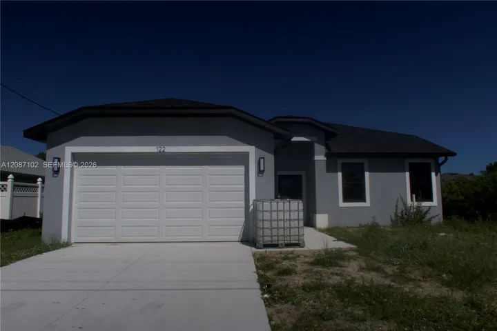 2 car driveway and 2 car garage. Single-story residence featuring a gray stucco exterior, a concrete driveway, a multi-car garage with a sectional door, and dark-toned shingle roofing