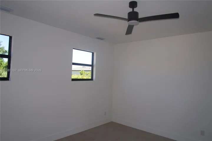 Neutral interior featuring neutral wall paint, carpeting, black-framed windows, and a matte black ceiling fan with an integrated light fixture