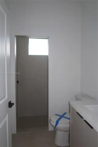 Bathroom 3, featuring a floating vanity with a light-toned countertop, a walk-in shower with large-format wall tile, a transom window, and matte black hardware